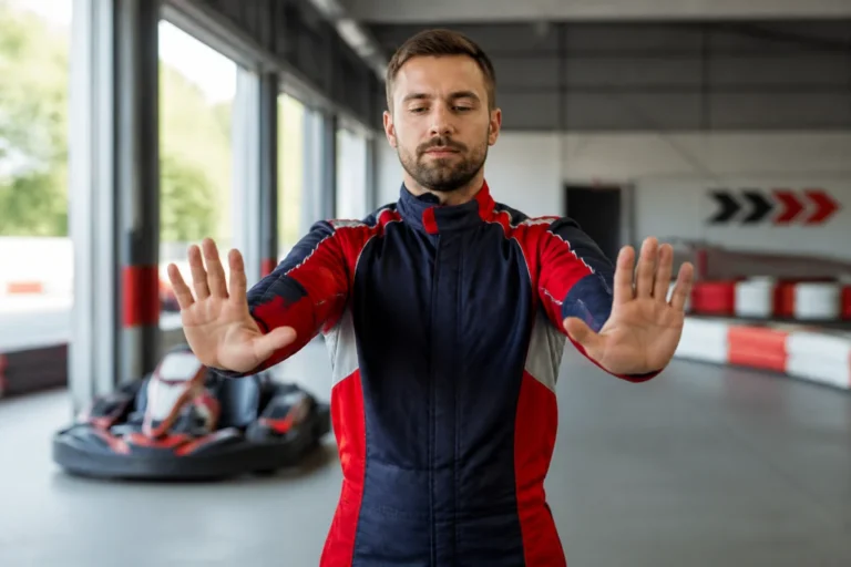 Pilote de karting réalisant des exercices d’échauffement des poignets avant une séance sur piste intérieure